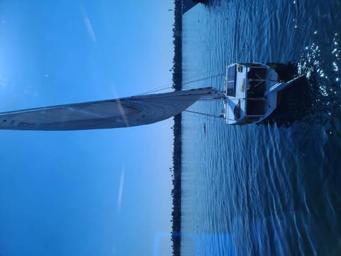 Sailboat on a river with clear blue skies.