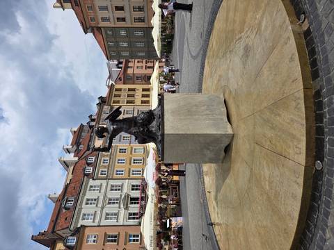 Statue of a mermaid in a square surrounded by buildings