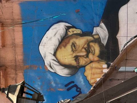       Street art of a man wearing a turban with finger pointing
  