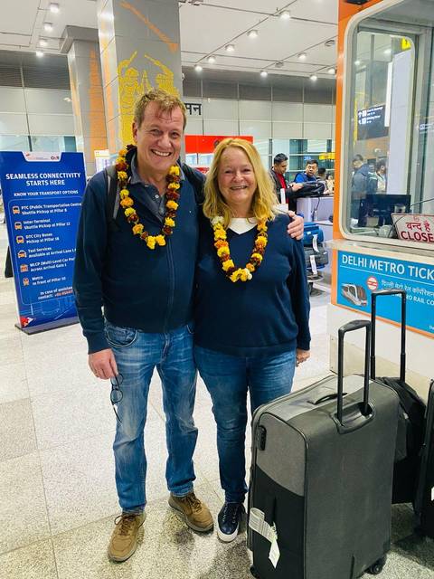       Two people with garlands in an airport with welcome signs
  