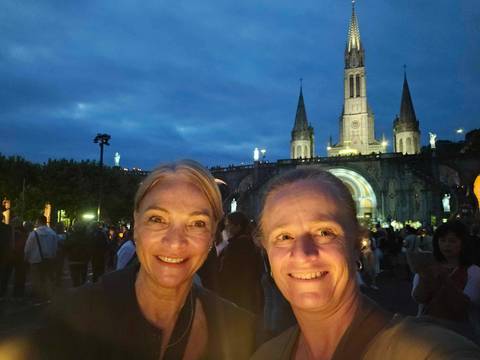       Two women smiling at night with a lit cathedral background
  