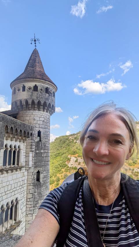       Woman smiling beside a stone castle tower
  