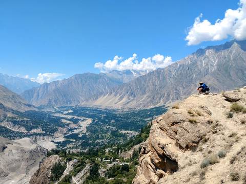 Person sitting on a cliff with a vast valley view