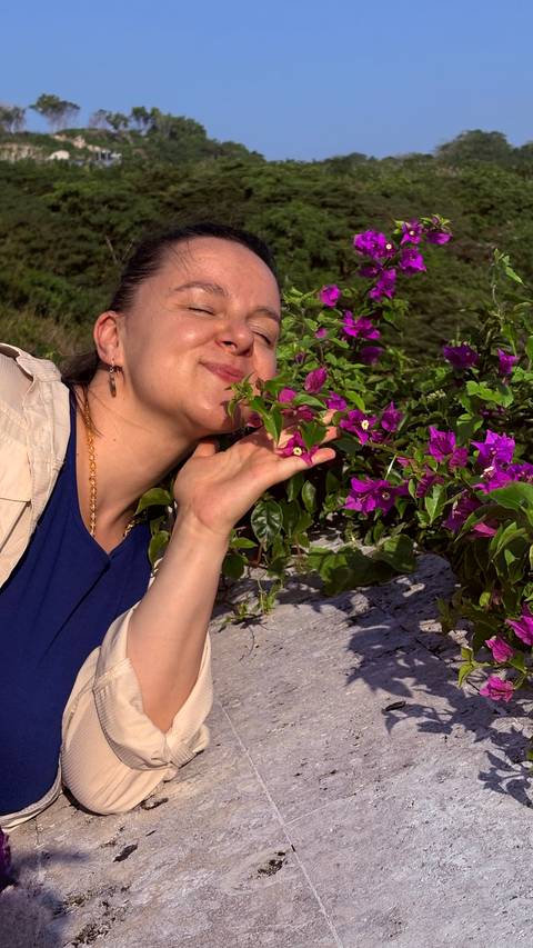       Person smelling vibrant purple flowers.
  