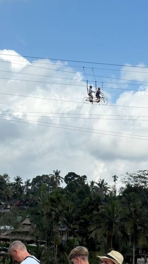 People cycling on a high wire.