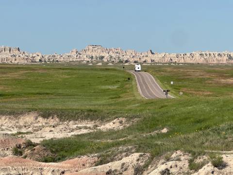       Road through green fields leading to rocky formations.
  