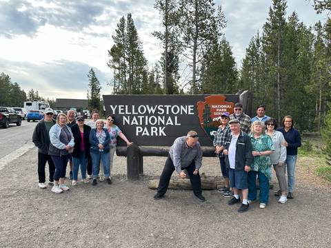       Group photo in front of the Yellowstone National Park sign.
  