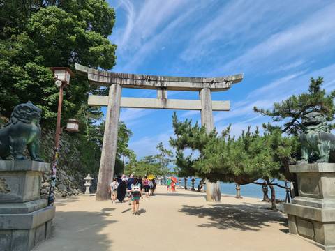       Tourists walking through a torii gate leading to a shrine.
  