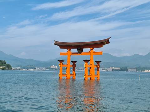       The floating torii gate in water with mountains in the background.
  