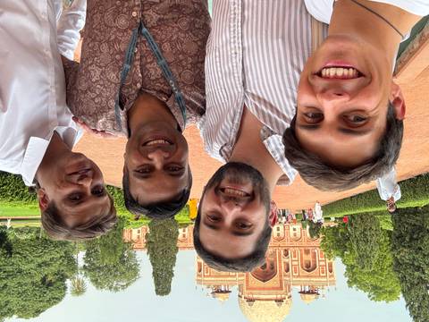       Group selfie in front of Humayun's Tomb with greenery.
  