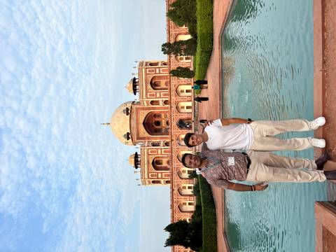 Two men standing in front of a Mughal-era building with water feature.