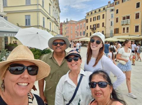       Group of people taking a selfie in a European street with buildings.
  