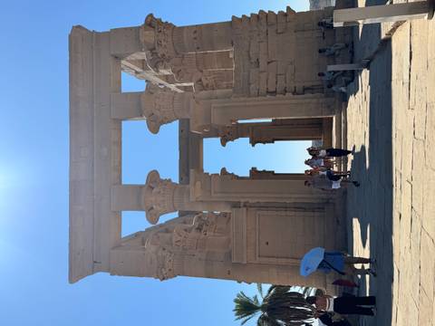       A group of tourists inside an ancient Egyptian temple with columns.
  