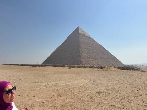 Partially visible person with a pyramid in the background.