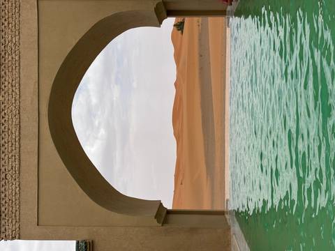      Desert view through arch with swimming pool in foreground.
  