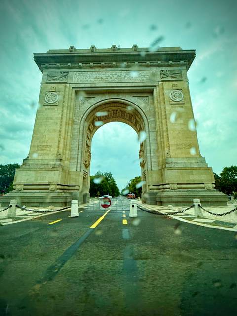 Men with ox cart on a dirt road through greenery.