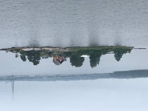       Small island with a house and trees, surrounded by water.
  
