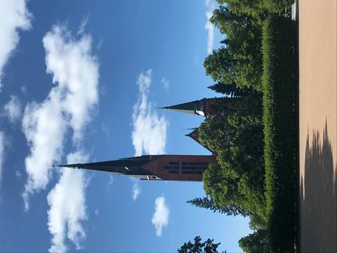 Large brick church with tall spires and blue sky.