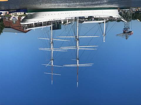 Tall ship with multiple masts docked at port.
