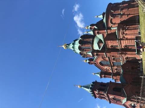       Elegant red brick cathedral against a blue sky.
  