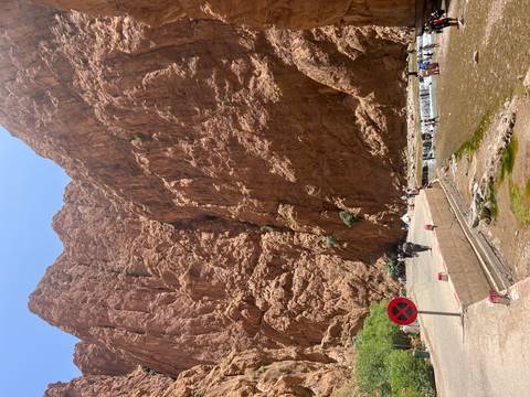 Tall cliffs with people walking near a river.