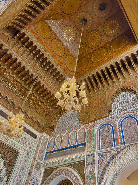 Ornately decorated ceiling with chandeliers in a historic building.
