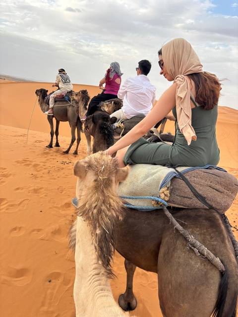       People riding camels in the desert.
  
