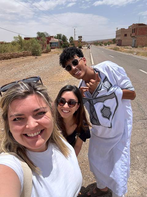       Three people taking a selfie on a road.
  