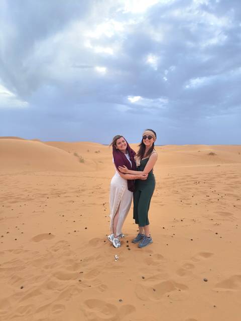       Two women in desert landscape smiling.
  