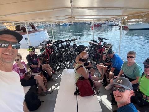 Cyclists group on a boat with bikes at a harbor.