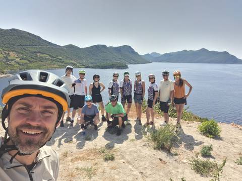 Group of cyclists with helmets posing by the sea.