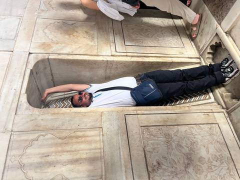 Person posing inside a narrow marble archway.
