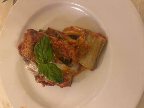 Dish with a tomato and cheese base topped with basil.