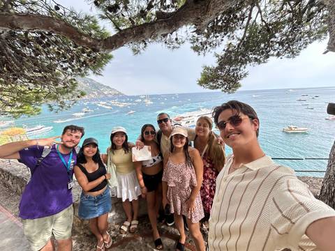 Group of people posing with a view of a bay full of boats.