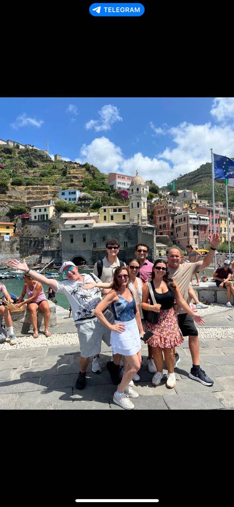       Group of people joyfully posing with colorful buildings and water behind.
  