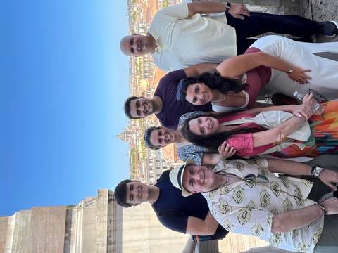       Group of people posing with a cityscape in the background
  