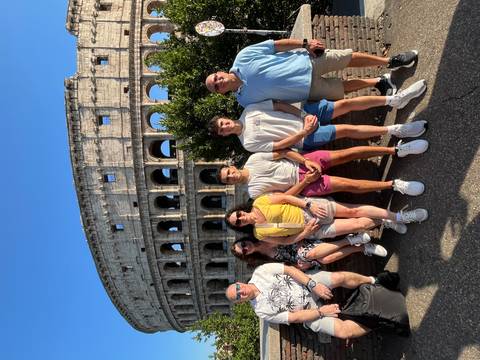       Group of people posing in front of the Colosseum
  