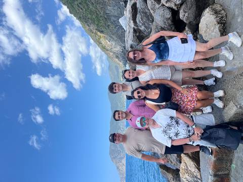       Group of people posing on rocks by the sea
  