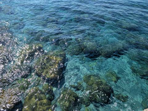 Clear blue water with visible rocks underneath