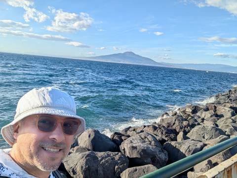 Person taking a selfie in front of a sea view and Mount Vesuvius
