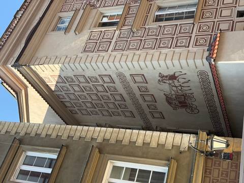 Building facade with artwork depicting a carriage and horses.