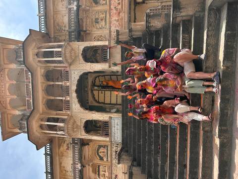 Group celebrating Holi with colors at a historic site.