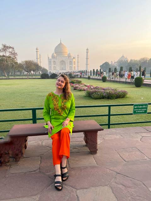 Woman sitting on a bench with the Taj Mahal in the background.