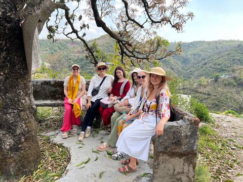 Group of people sitting on a stone bench enjoying a scenic view.