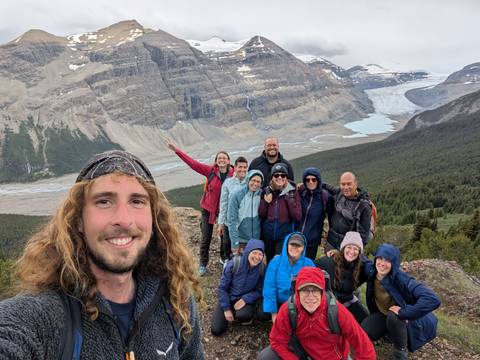 Group of hikers posing with a mountainous landscape in the background.