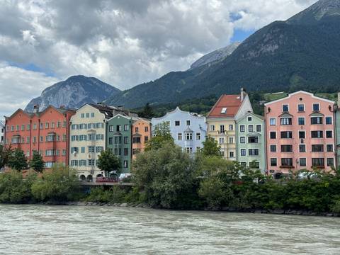 Row of colorful buildings along a river with mountains.