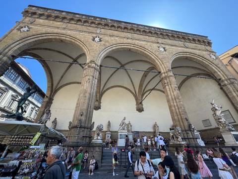People observing statues under arches in Florence.