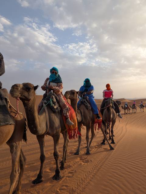 Group of people riding camels in the desert.