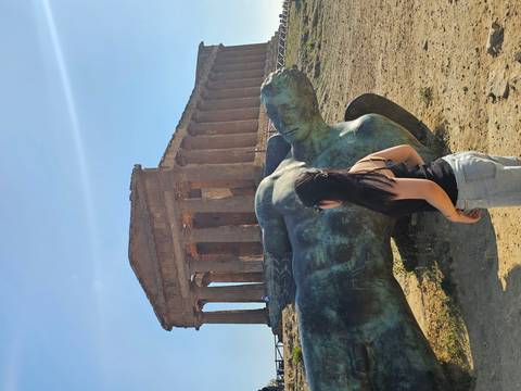 Woman observing a fallen statue and ancient temple.