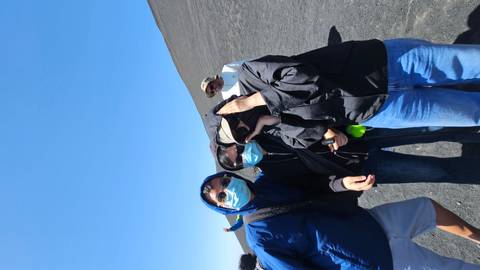 People on a rocky hillside with windblown clothing.